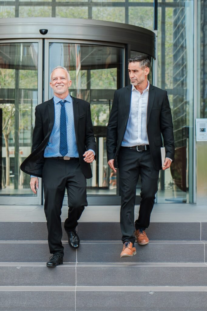 Vertical. Confident business men walking down the staircase, talking about the corporate finance